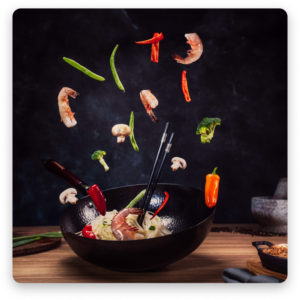 An exciting image of a stir-fry being tossed in a wok, with fresh ingredients flying through the air in mid-air.