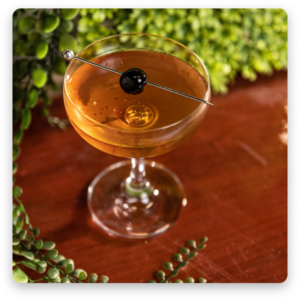 A sophisticated image of a martini, with clear liquid in a classic martini glass, garnished with an olive on a toothpick.